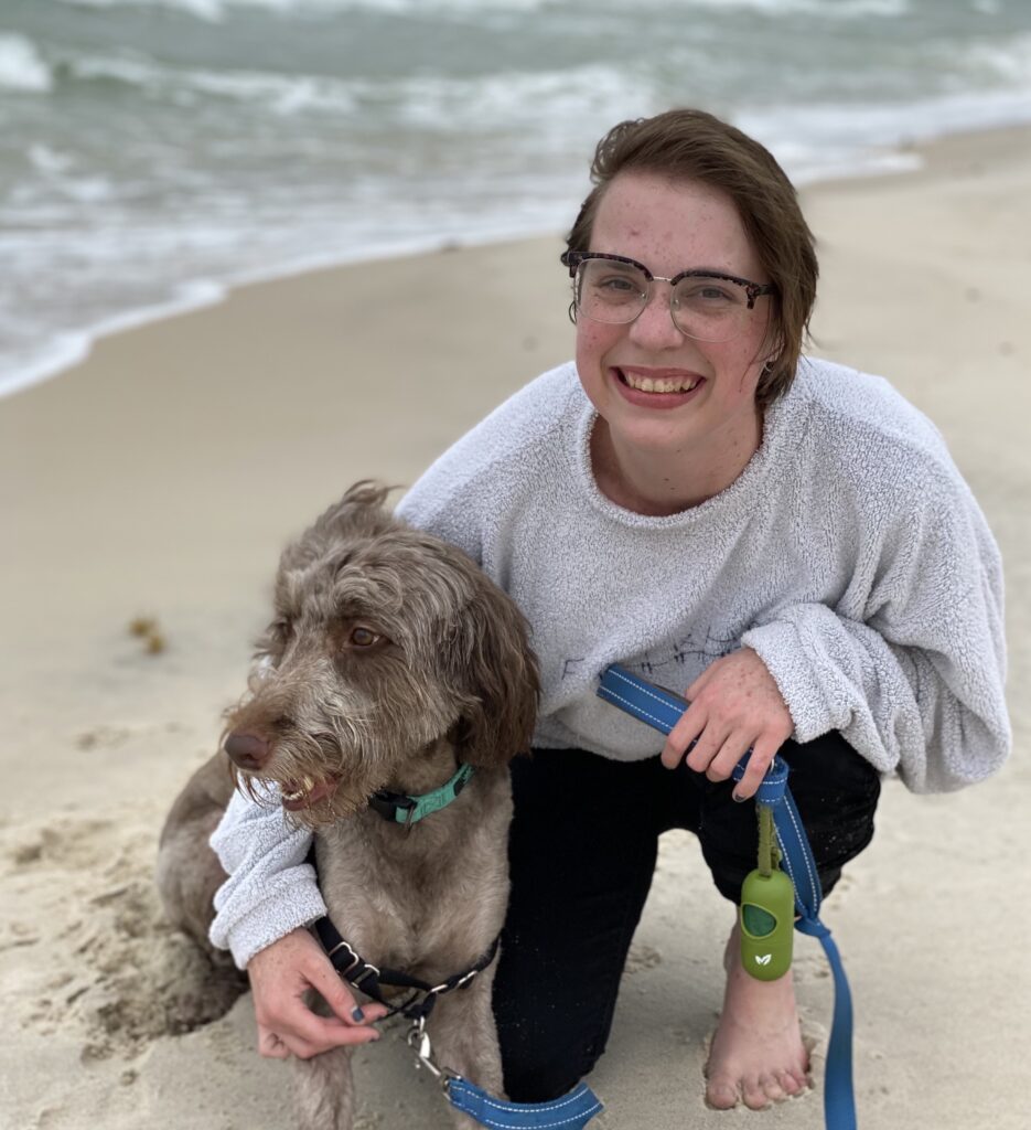 Entler with glasses and short hair on a beach with a dog 